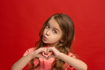 Image showing The happy teen girl standing and smiling against red background.