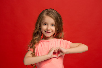 Image showing The happy teen girl standing and smiling against red background.