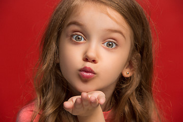 Image showing The happy teen girl standing and smiling against red background.