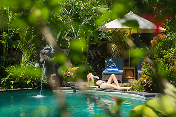 Image showing Sensual young woman relaxing in outdoor spa infinity swimming pool surrounded with lush tropical greenery of Ubud, Bali.