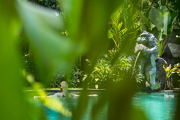 Image showing Sensual young woman relaxing in outdoor spa infinity swimming pool surrounded with lush tropical greenery of Ubud, Bali.