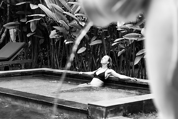 Image showing Sensual young woman relaxing in outdoor spa infinity swimming pool surrounded with lush tropical greenery of Ubud, Bali. Black and white image.