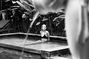 Image showing Sensual young woman relaxing in outdoor spa infinity swimming pool surrounded with lush tropical greenery of Ubud, Bali. Black and white image.