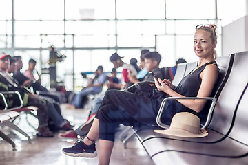 Image showing Female traveler using her cell phone while waiting to board a plane at departure gates at asian airport terminal.