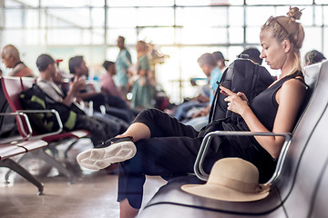 Image showing Female traveler using her cell phone while waiting to board a plane at departure gates at asian airport terminal.