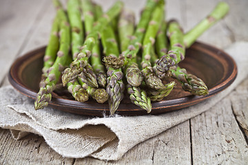 Image showing Fresh raw garden asparagus closeup on brown ceramic plate and li