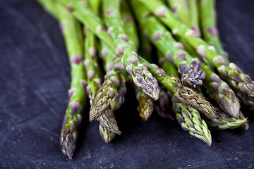 Image showing Organic fresh raw garden asparagus closeup on black board backgr