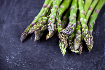 Image showing Organic fresh raw garden asparagus closeup on black board backgr