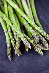 Image showing Organic fresh raw garden asparagus closeup on black board backgr