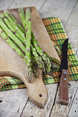 Image showing Raw garden asparagus and knife closeup on cutting board on rusti