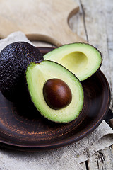 Image showing Fresh organic avocado on ceramic plate and linen napkin on rusti