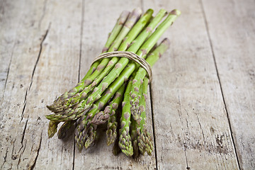 Image showing Bunch of fresh raw garden asparagus on rustic wooden table backg