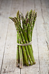 Image showing Bunch of fresh raw garden asparagus on rustic wooden table backg