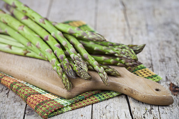 Image showing Organic raw garden asparagus on cutting board on rustic wooden t