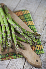 Image showing Organic raw garden asparagus on cutting board on rustic wooden t