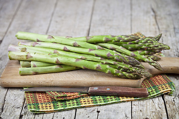 Image showing Organic raw garden asparagus and knife closeup on cutting board 