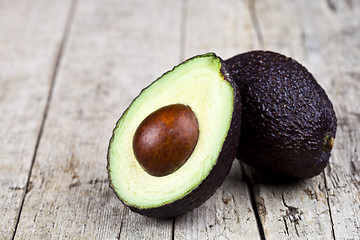 Image showing Fresh organic avocado halves on old wooden table background. Fre