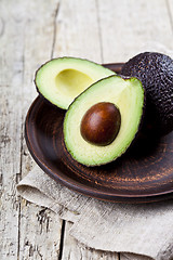 Image showing Fresh organic avocado on ceramic plate and linen napkin on rusti