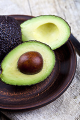 Image showing Fresh organic avocado on ceramic plate and linen napkin on rusti