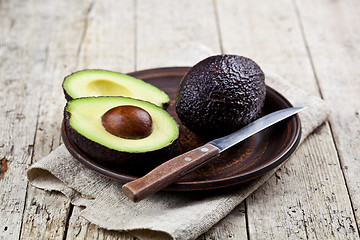 Image showing Fresh organic avocado on ceramic plate and knife on  linen napki