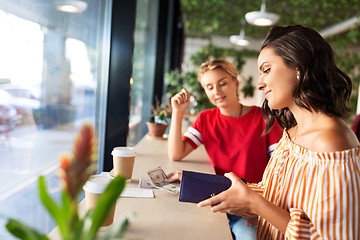 Image showing female friends paying for coffee at cafe