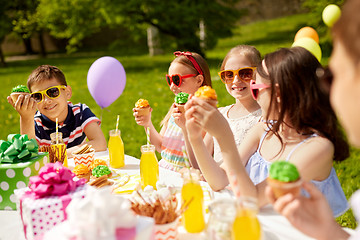 Image showing kids eating cupcakes on birthday party in summer