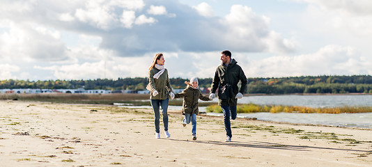 Image showing happy family running along autumn beach