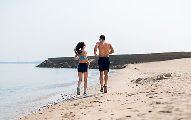 Image showing couple in sports clothes running along on beach