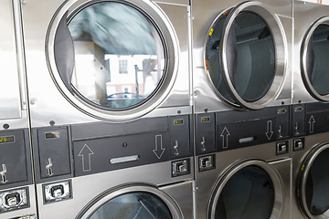 Image showing washing machines with clothes inside at laundromat