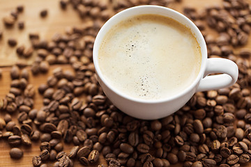 Image showing close up coffee cup and beans on wooden table