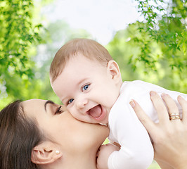 Image showing mother kissing baby over green natural background