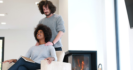 Image showing multiethnic couple hugging in front of fireplace