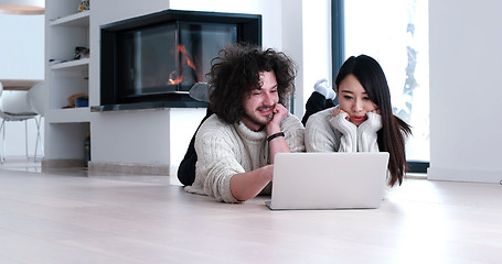 Image showing young multiethnic couple using a laptop on the floor