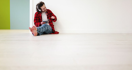 Image showing young man listenig music on tablet at home