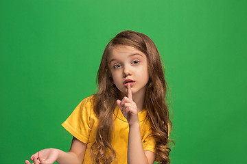 Image showing The young teen girl whispering a secret behind her hand over green background