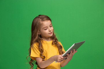 Image showing Little funny girl with tablet on green background