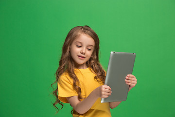 Image showing Little funny girl with tablet on green background