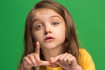 Image showing The young teen girl whispering a secret behind her hand over green background