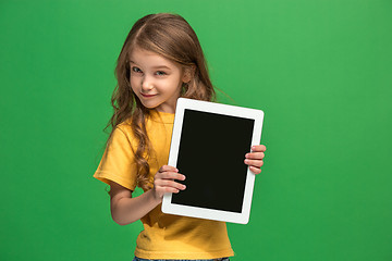 Image showing Little funny girl with tablet on green background