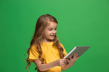 Image showing Little funny girl with tablet on green background