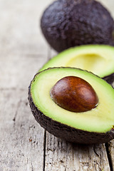 Image showing Avocado on old wooden table background. Fresh avocado halves on 