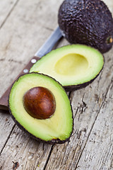 Image showing Fresh organic avocado and knife on old wooden table background. 