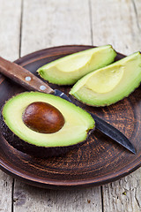 Image showing Fresh organic avocado on ceramic plate and knife on rustic woode