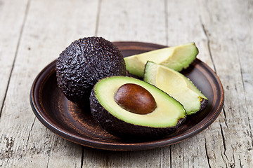 Image showing Fresh organic avocado on ceramic plate on rustic wooden table ba