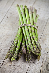 Image showing Bunch of fresh raw garden asparagus on rustic wooden table backg