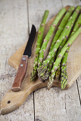 Image showing Fresh raw garden asparagus and knife closeup on cutting board on