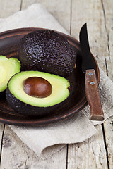 Image showing Fresh organic avocado on ceramic plate and knife on  linen napki