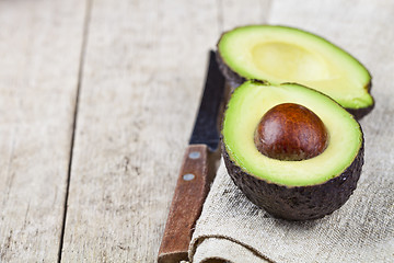 Image showing Avocado and knife on linen napkin old wooden table background. F