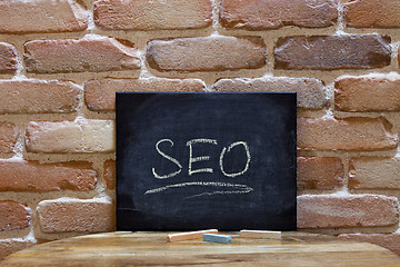 Image showing Black board with the word SEO drown by hand on wooden table on b