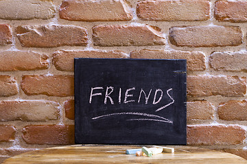 Image showing Black board with the word FRIENDS drown by hand on wooden table 